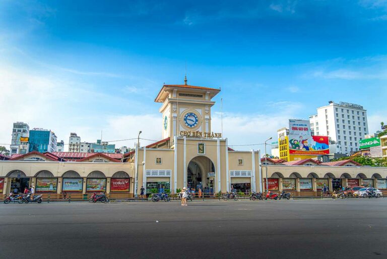Vooraanzicht van Ben Thanh Market in Ho Chi Minh City, met de iconische kloktoren, druk verkeer en marktkramen in het hart van Saigon