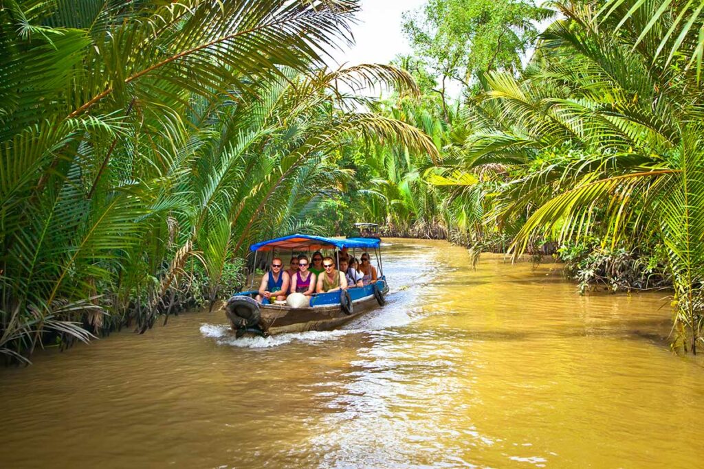 Kleine motorboot met reizigers vaart door een palmrijk kanaal in Ben Tre, Mekong Delta – boottocht Mekong Delta Vietnam