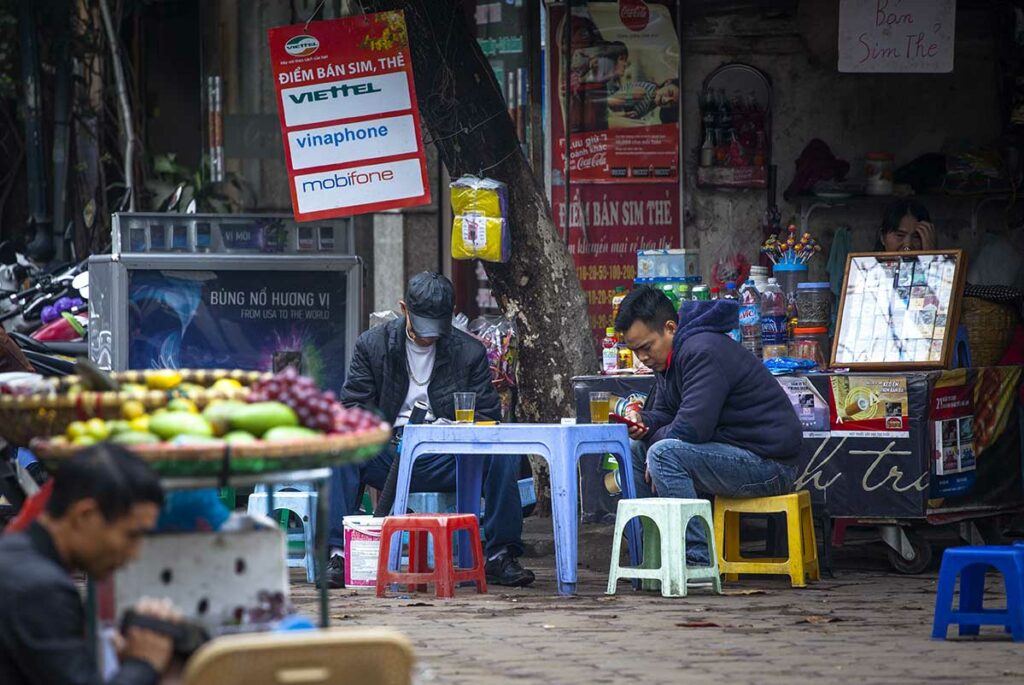 Mannen die bia hoi bier drinken aan kleine tafeltjes op straat in Vietnam, typisch voorbeeld van lokale bierdrinkcultuur en dagelijks sociaal leven