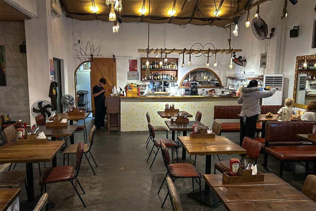 Interieur van Bikini Bottom Express in An Bang Hoi An met houten tafels en informele sfeer