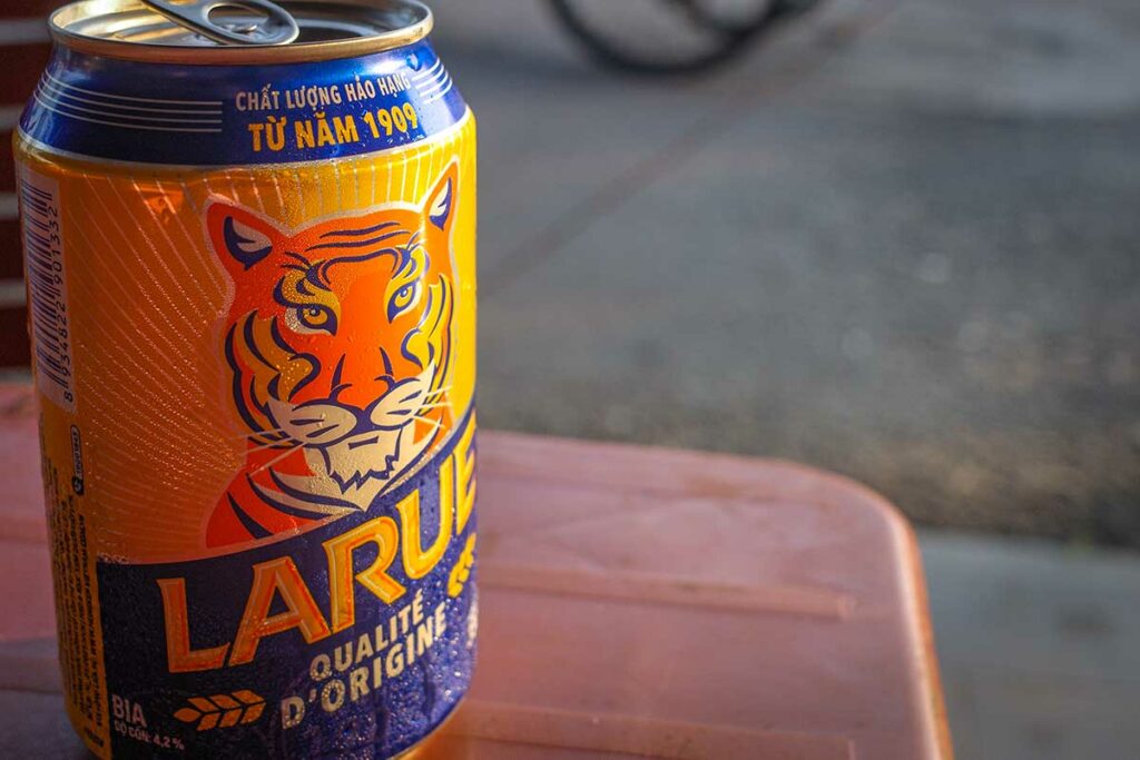 Blikje Biere Larue bier op een plastic tafeltje langs de straat in Vietnam, een populair lokaal bier uit Centraal-Vietnam dat vaak wordt gedronken bij informele eetgelegenheden