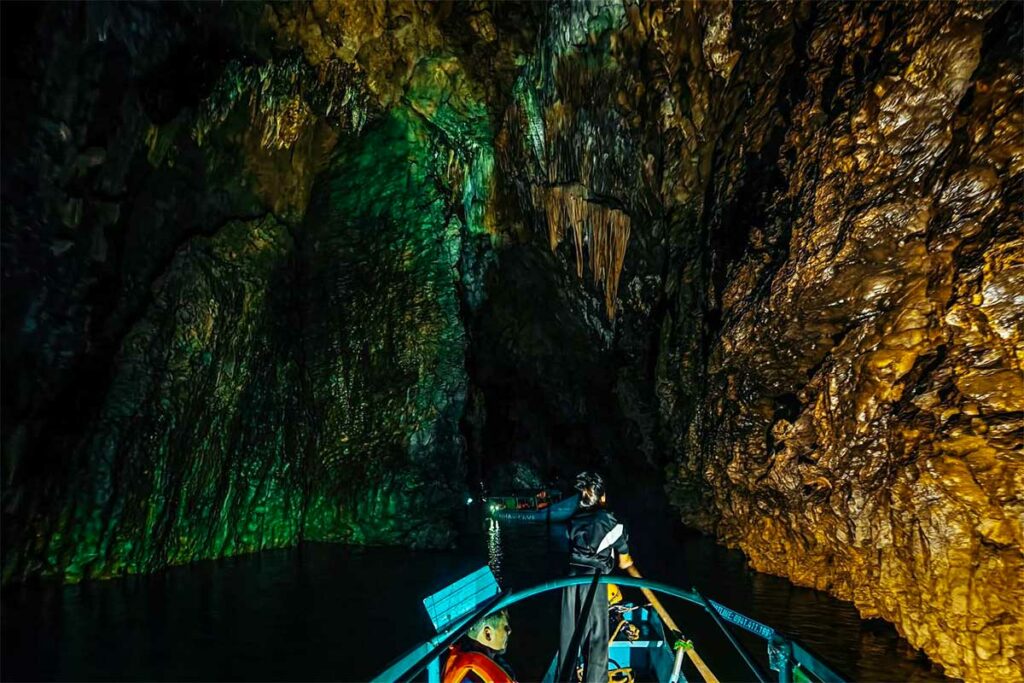 Boottocht door Phong Nha Cave, waarbij bezoekers per boot door de verlichte grot varen langs rotswanden en ondergrondse rivier.