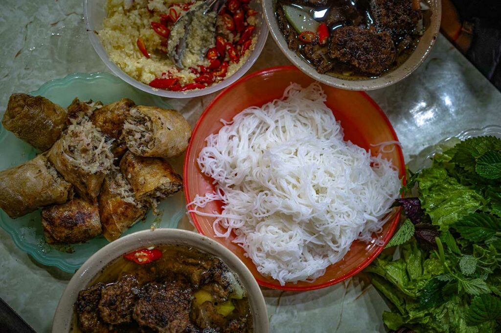 Bún chả met gegrild varkensvlees, rijstnoedels, verse kruiden en dipsaus, geserveerd als los samengestelde onderdelen