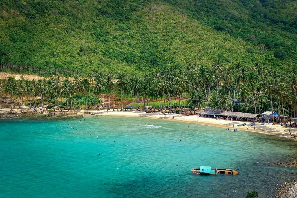 Cai Man strand op Nam Du eiland met turquoise zee en palmbomen langs de baai