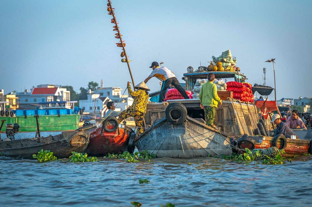 Handelaren die goederen overladen tussen boten op de Cai Rang drijvende markt bij Can Tho, een van de grootste en meest levendige markten in de Mekong Delta