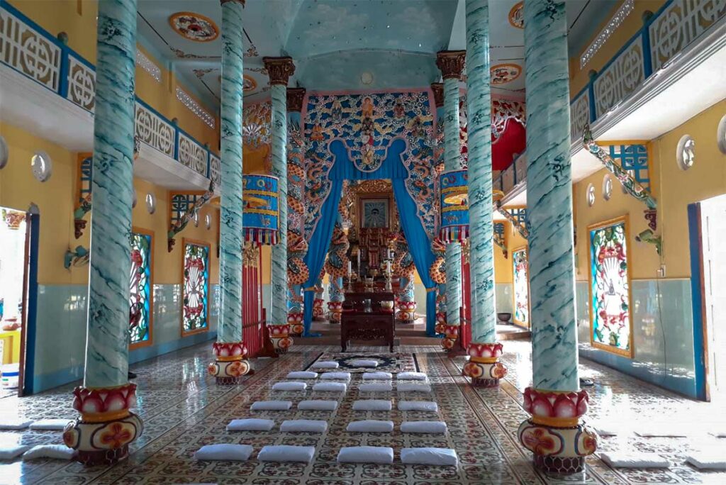 Interieur van de Cao Dai tempel in Ca Mau met turquoise zuilen en gebedsruimte