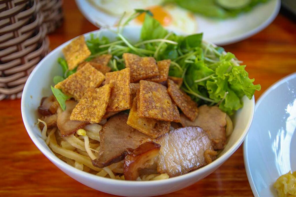 Cao lầu noedelgerecht met varkensvlees, kruiden en knapperige rijstcrackers, een typisch Vietnamees gerecht uit Hoi An