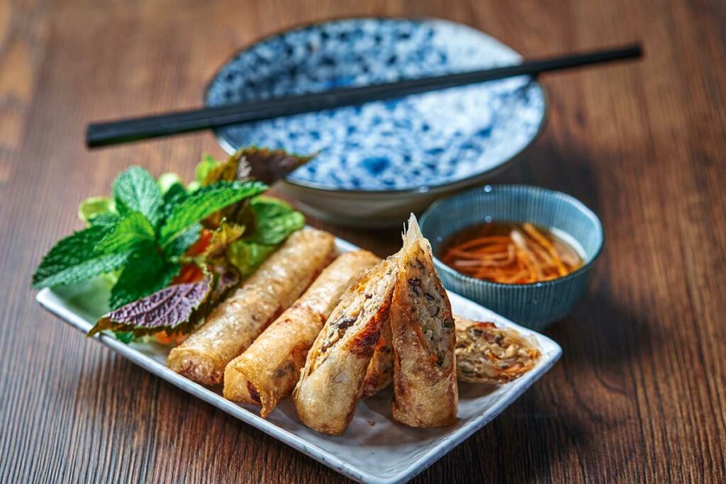Chả giò, Vietnamese gefrituurde loempia’s met vlees en groenten, geserveerd met verse kruiden en dipsaus, een klassiek Vietnamees gerecht