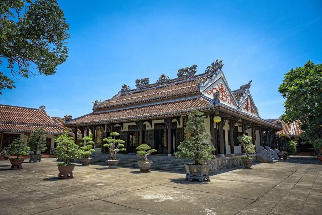 Hoofdgebouw van Chuc Thanh Pagoda in Hoi An met bonsaibomen en rustige binnenplaats