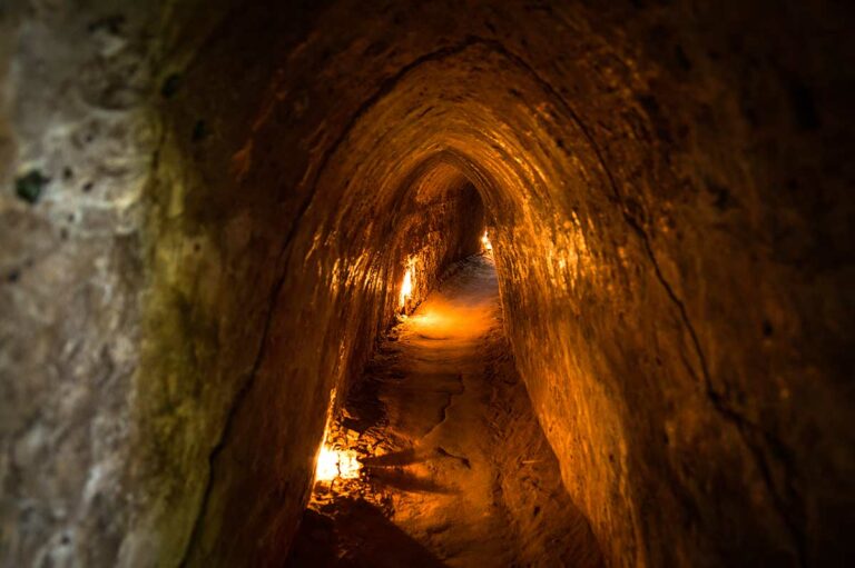 Smalle ondergrondse tunnelgang van het Cu Chi Tunnels netwerk, verlicht om bezoekers een beeld te geven van het leven onder de grond