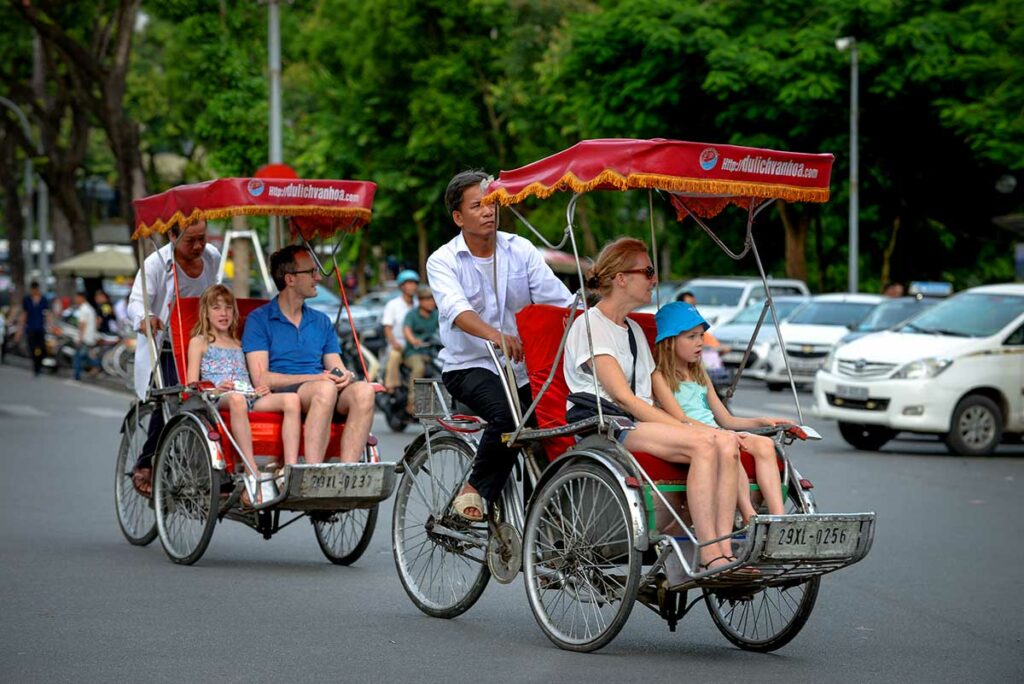 Toeristen in een cyclo riskja rijden door de Old Quarter van Hanoi tussen druk verkeer