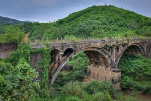 De Dau Mau-brug langs de Ho Chi Minh Trail, een historisch overblijfsel uit de Vietnamoorlog, midden in groen landschap.