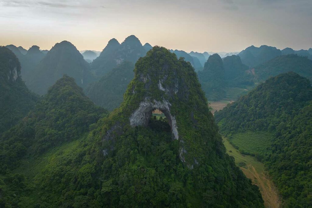 Dronebeeld van Angel Eye Mountain (God’s Eye Mountain) met het grote natuurlijke gat in de berg, gelegen in een afgelegen karstlandschap in Cao Bang.