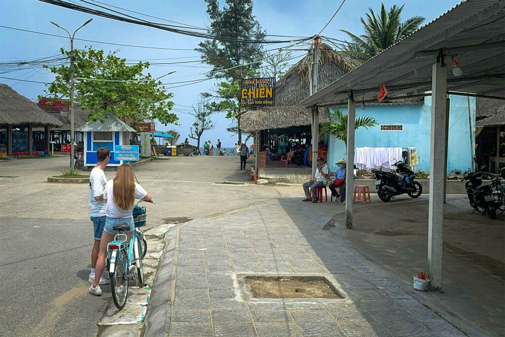 Reizigers fietsen door An Bang dorp bij Hoi An richting het strand