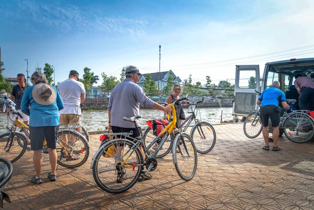 Toeristen met fietsen aan de rivier in Soc Trang tijdens fietstocht door de Mekong Delta