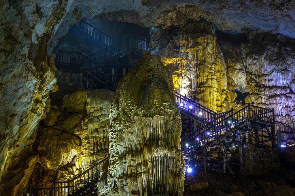 Houten trap en loopbrug langs een grote kalksteenformatie in Paradise Cave, waar bezoekers afdalen in het toegankelijke deel van de grot.