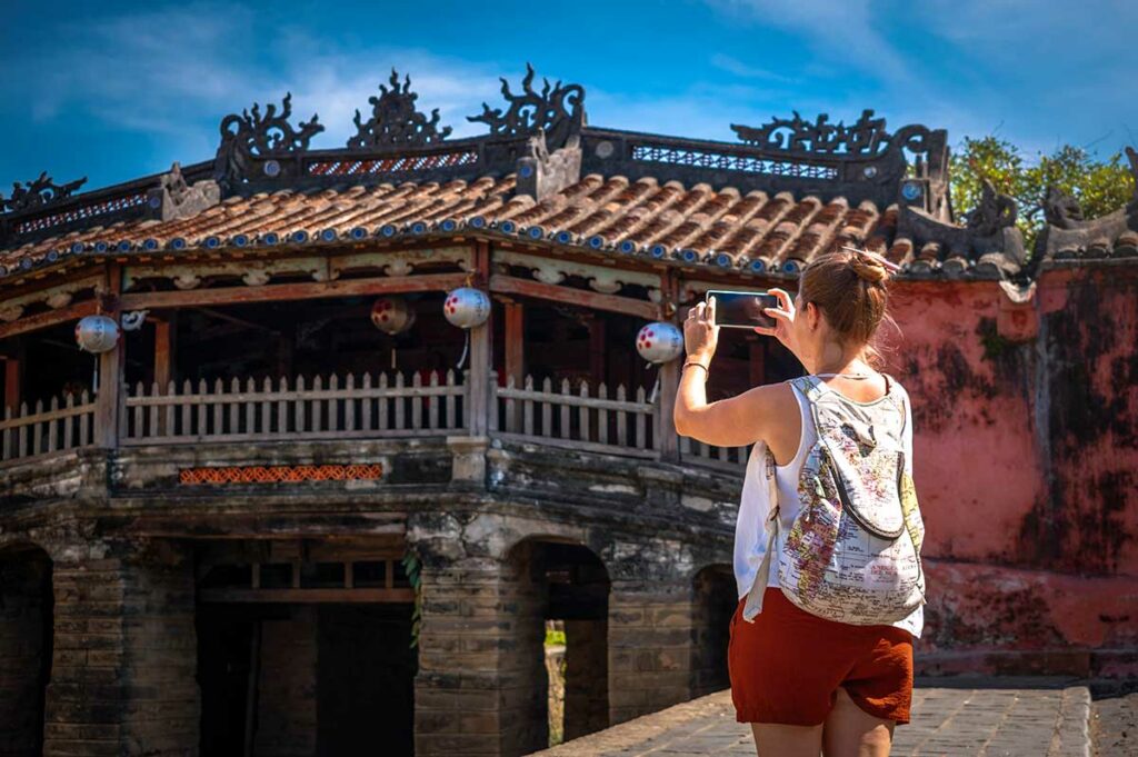 Toerist maakt foto van de Japanse Brug in Hoi An met houten dak en pagode in het oude centrum