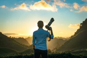 Fotograaf met camera tijdens zonsopkomst in de heuvels van Vietnam, een klassiek moment voor landschapsfotografie bij zacht ochtendlicht.