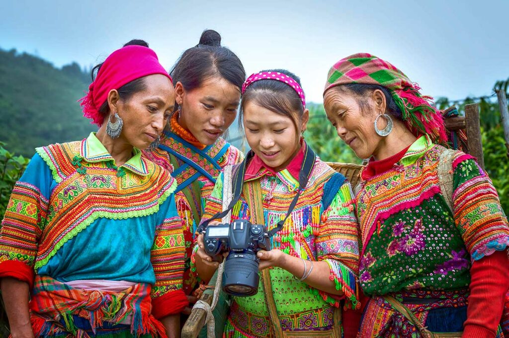 Fotograaf toont foto’s aan vrouwen in traditionele kleding in Ha Giang, een mooi moment van portretfotografie en culturele fotografie in Noord-Vietnam.