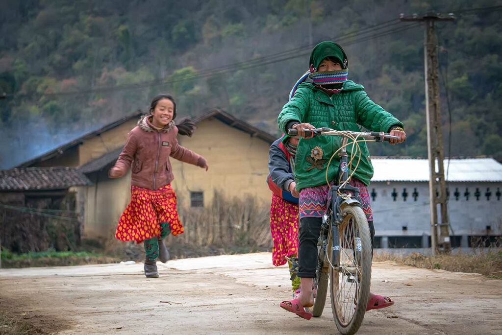 Kinderen in warme kleding op het platteland van Ha Giang tijdens de winter met bergachtig landschap op de achtergrond