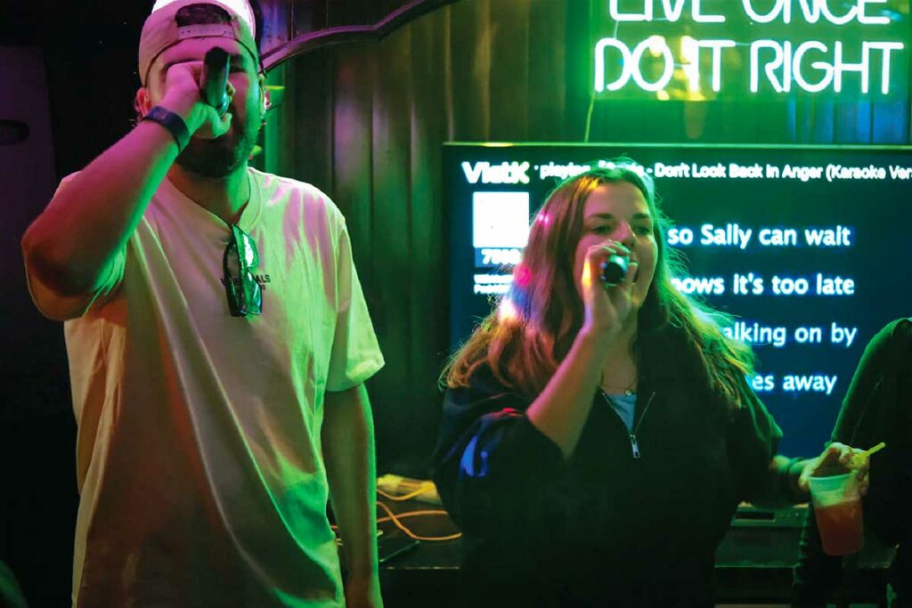 Backpackers zingen karaoke in een bar in Vietnam, typisch voorbeeld van toeristische karaoke-ervaring tijdens het reizen