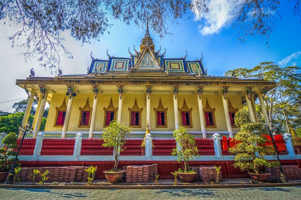 Gevel van Hang Pagoda in Tra Vinh met zuilengalerij, kleurrijk dakpatroon en rode ramen