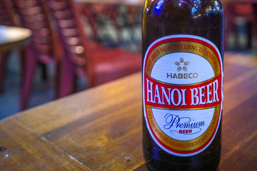 Fles Hanoi Beer Premium op een houten tafel in een lokaal restaurant, een klassiek Noord-Vietnamees bier dat veel wordt gedronken bij eenvoudige maaltijden