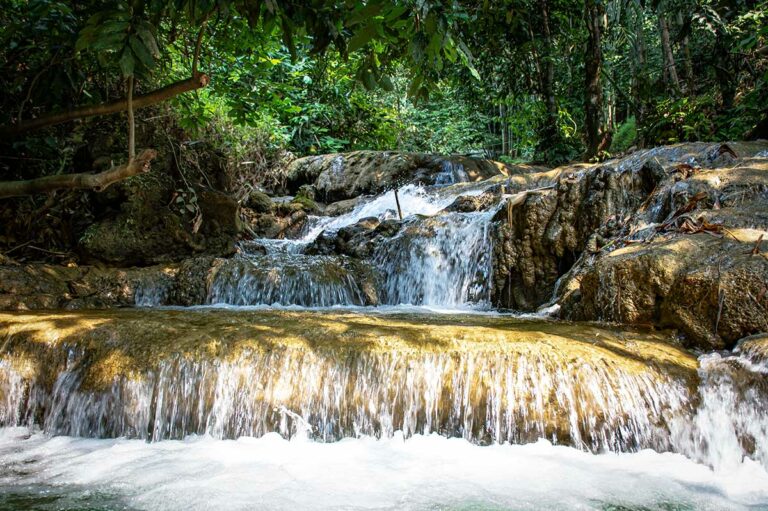 Kleine junglewaterval bij Hieu Falls in Pu Luong Nature Reserve, met helder water dat over rotsen stroomt tussen dicht groen