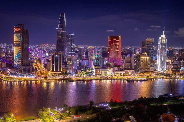 Nachtelijke skyline van Ho Chi Minh City langs de Saigon River, met verlichte wolkenkrabbers, stadslichten en reflecties op het water