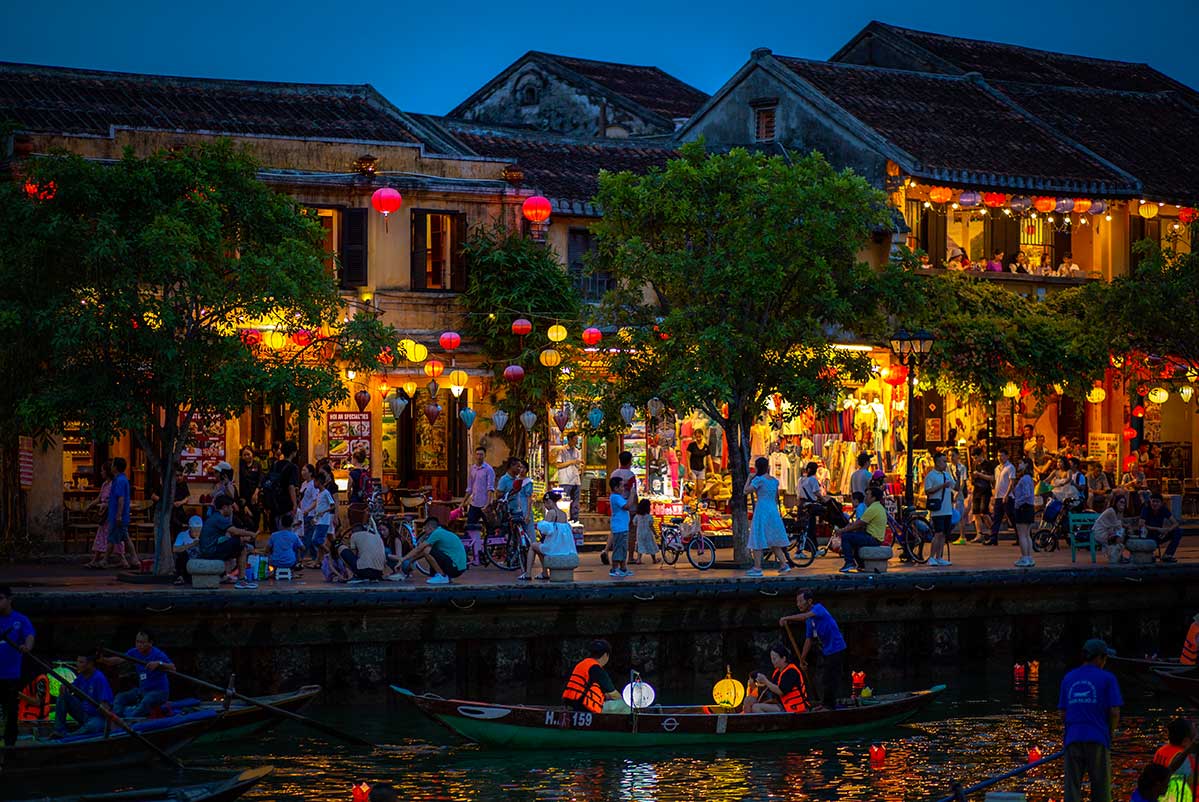 Avondsfeer tijdens het Hoi An Lantern Festival met verlichte historische huizen langs de Hoai rivier en bezoekers die langs de kade wandelen