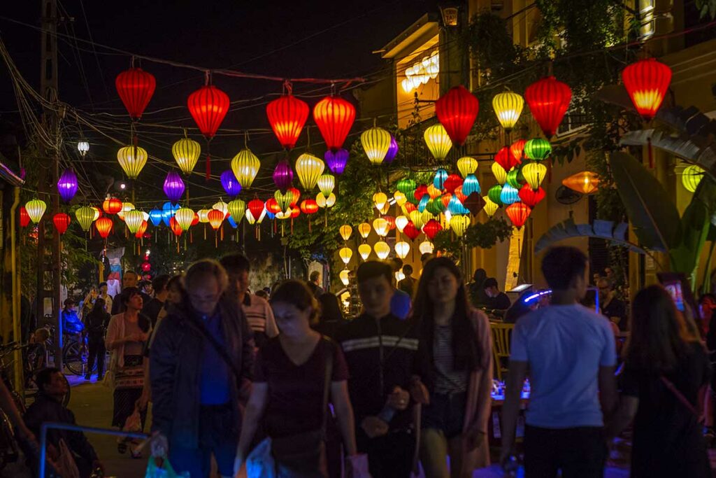 Drukke straat in Hoi An Ancient Town tijdens het Lantern Festival met tientallen kleurrijke zijden lampionnen boven de straat