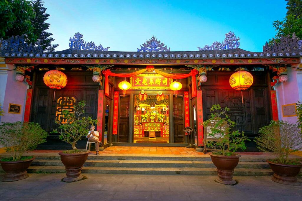 Verlichte tempel in Hoi An tijdens het Lantern Festival met rode lampionnen en bezoekers bij de ingang