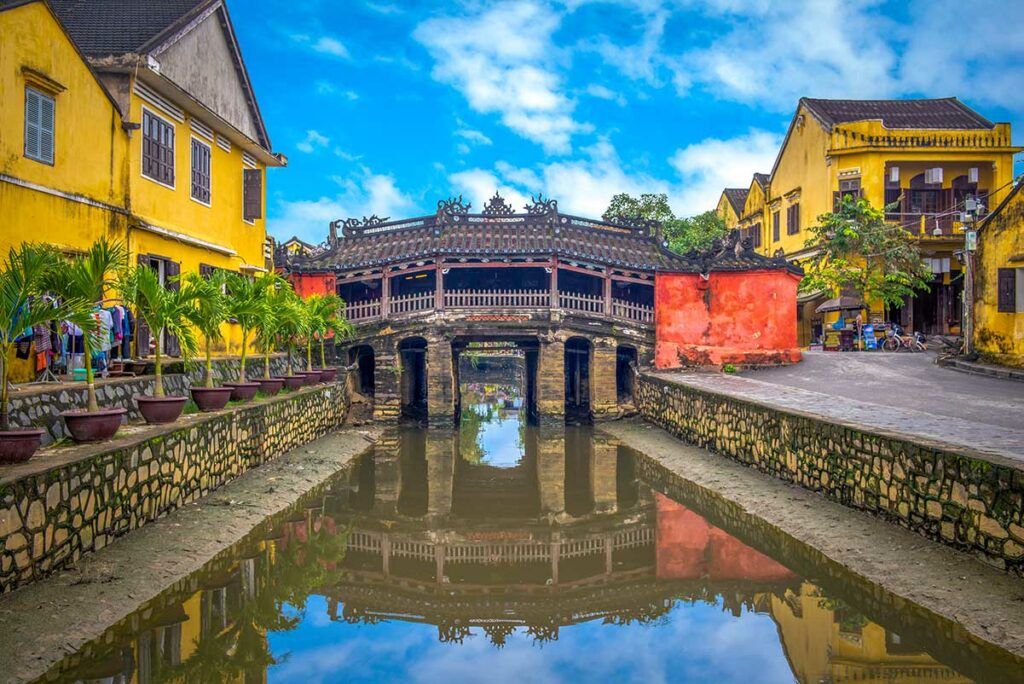 Japanse Brug in Hoi An over smal kanaal tussen gele historische huizen in de oude stad