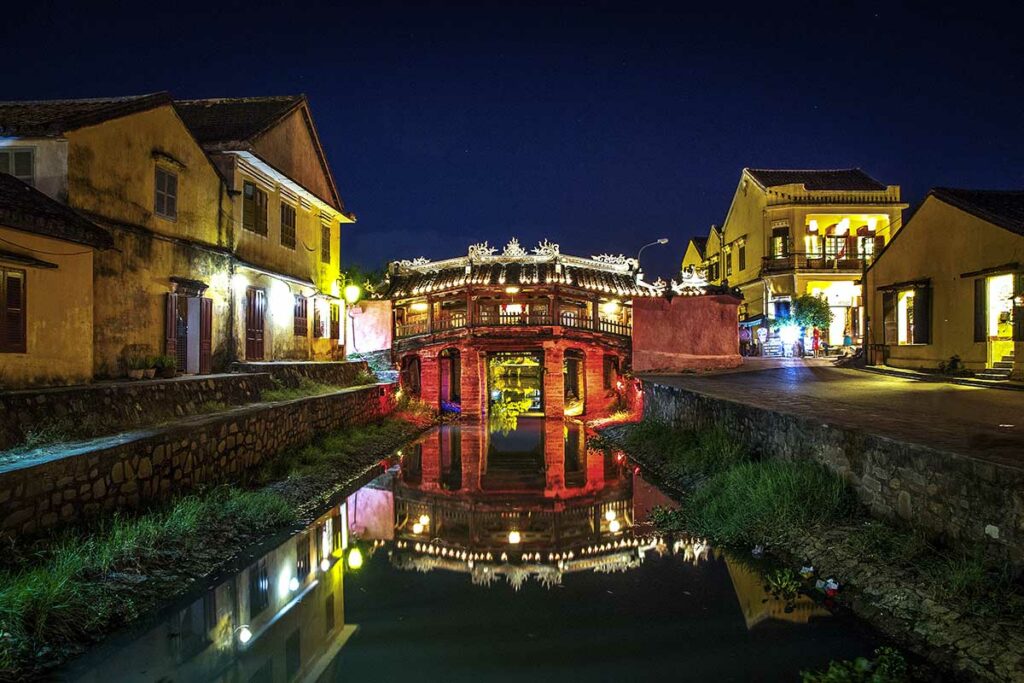 Japanse Brug in Hoi An ’s avonds verlicht met reflectie in het water van het kanaal