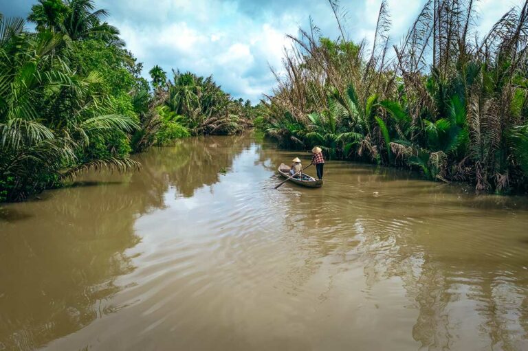 Boottocht door smalle kanalen in Ben Tre, Mekong Delta, met lokale roeiers in een traditionele sampan omringd door palmbomen – kanalen Mekong Delta Vietnam