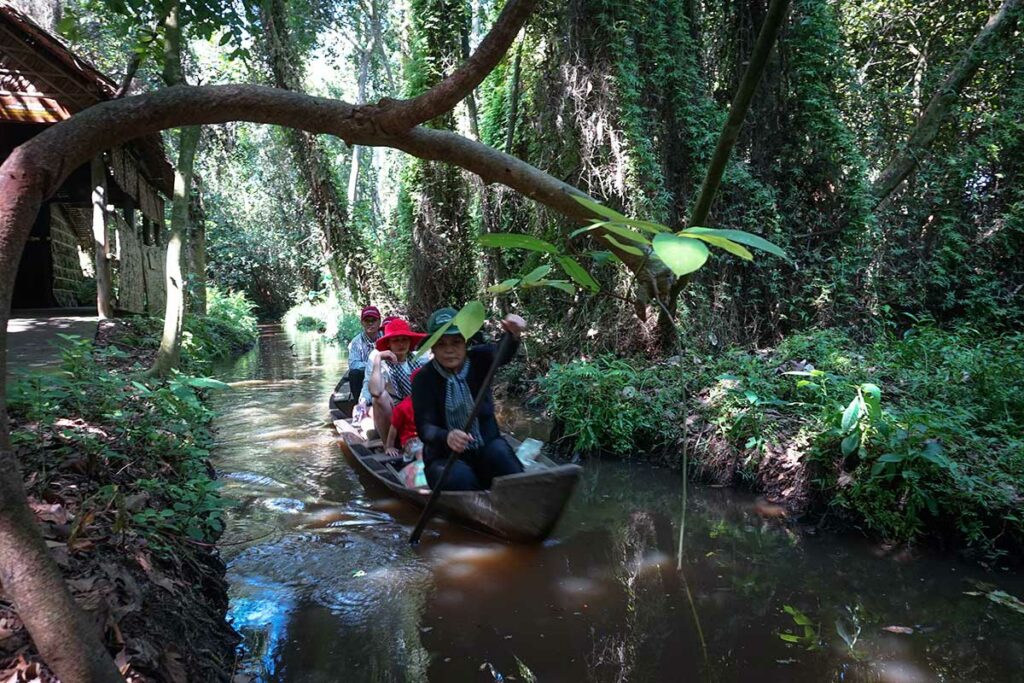 Rowboat passing through shaded canal in Xeo Quyt Forest Mekong Delta