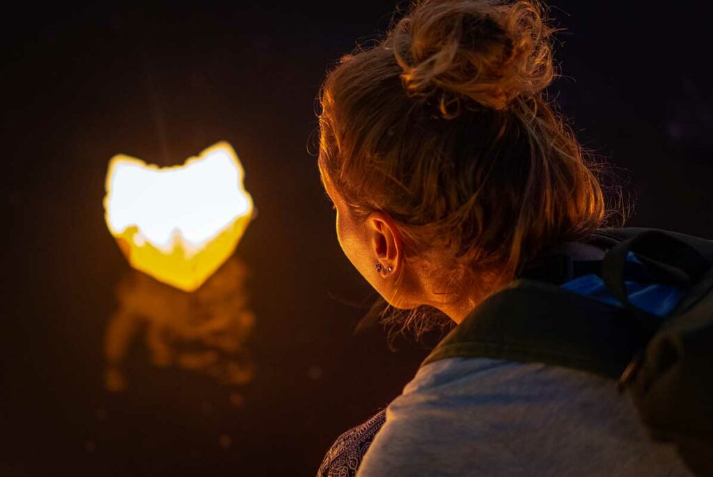Toerist laat een papieren lampion te water op de Hoai rivier tijdens het Hoi An Lantern Festival