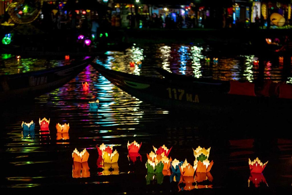 Drijvende papieren lampionnen op de Hoai rivier tijdens het Hoi An Lantern Festival met kleurrijke reflecties op het water