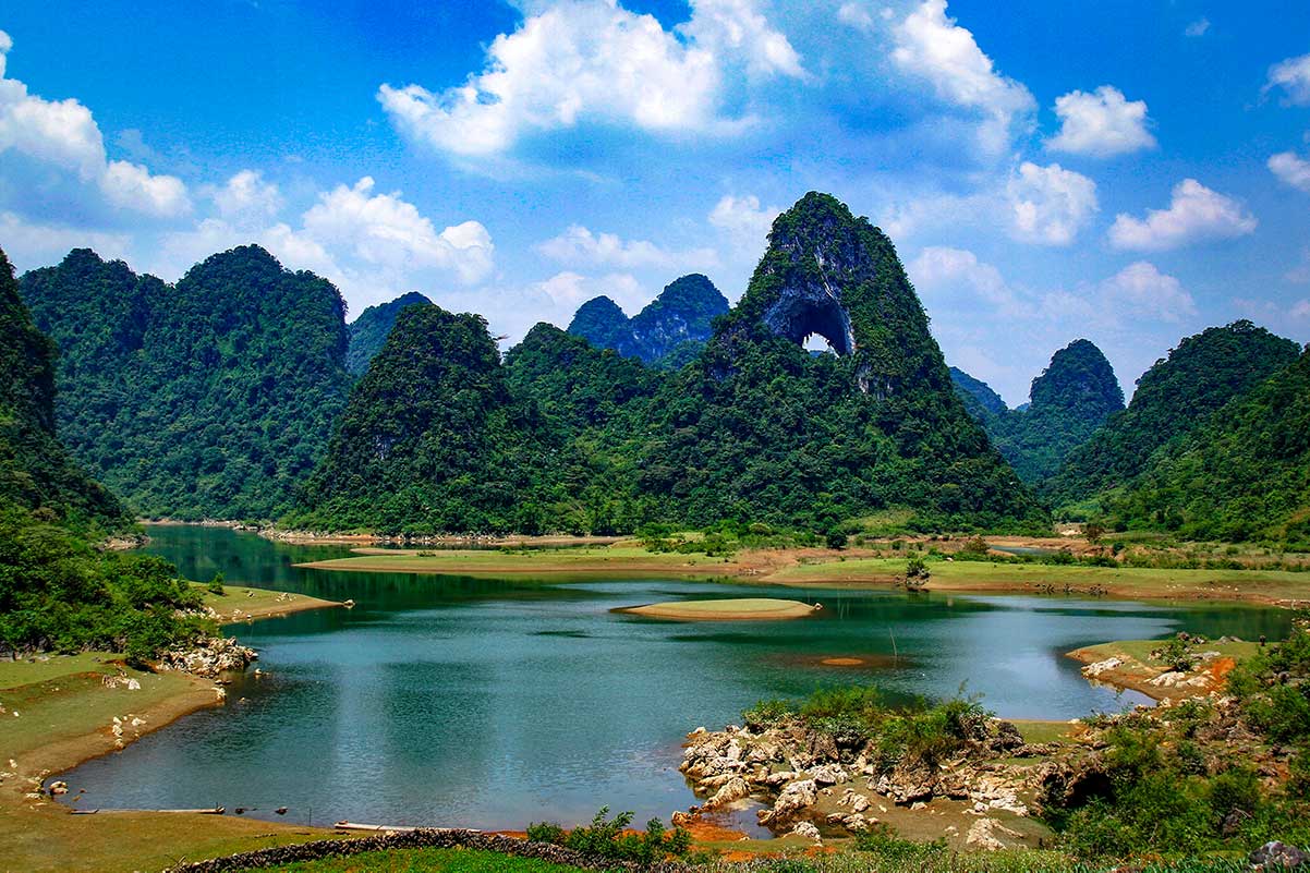 Panoramisch landschap rond Angel Eye Mountain met open grasvlaktes, meren en steile kalkstenen heuvels in de Tuyet Tinh Coc-vallei.