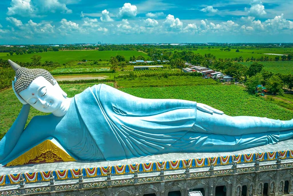 Grote liggende Boeddha bij Som Rong Pagode in Soc Trang met groen landschap van de Mekong Delta op de achtergrond