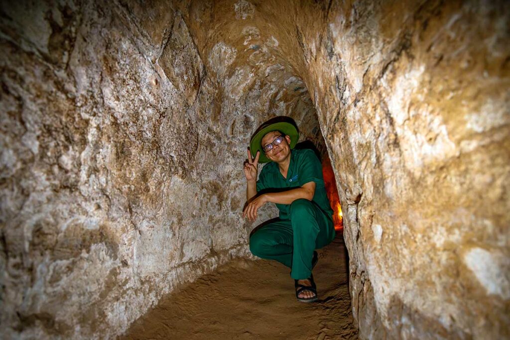 Lokale gids in de Cu Chi Tunnels die de smalle ondergrondse gangen demonstreert, een belangrijk historisch netwerk uit de Vietnamoorlog