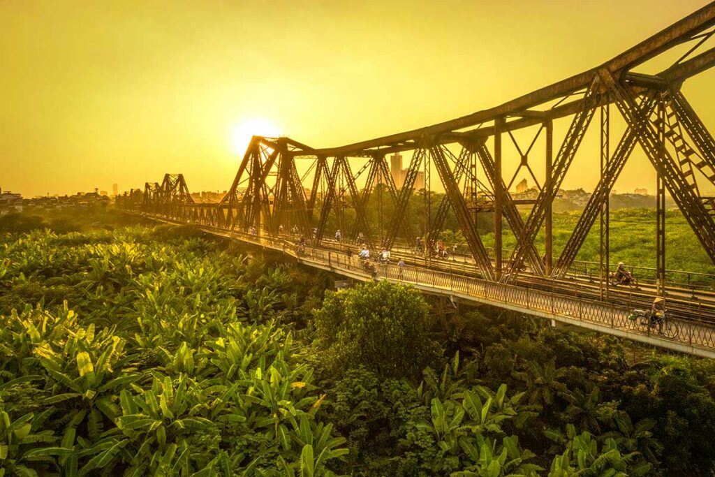 De Long Bien Bridge in Hanoi bij zonsondergang, een historische ijzeren brug uit de Franse koloniale tijd en een belangrijk symbool van de stad.