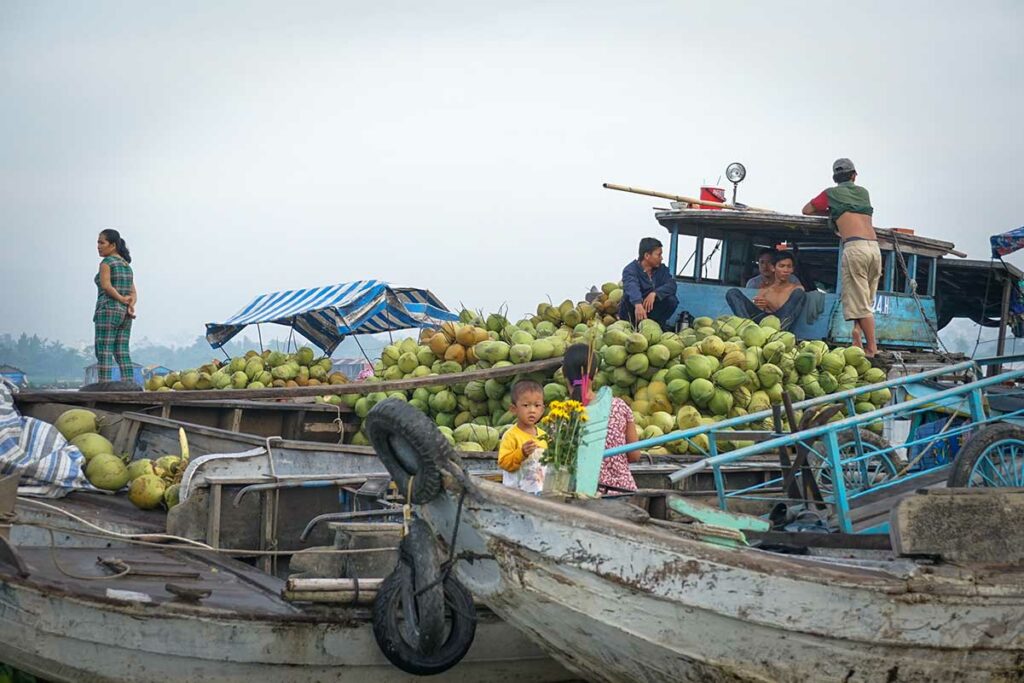 Drijvende markt in Long Xuyen met boot vol kokosnoten en handel op de rivier in de Mekongdelta