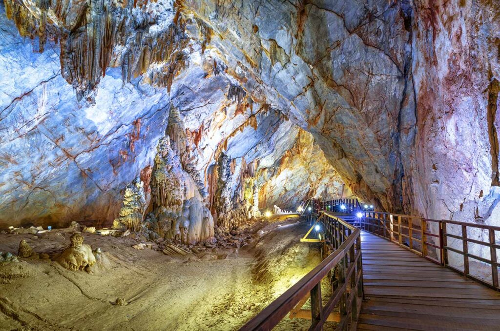 Houten wandelpad door een grote grotzaal van Paradise Cave in Phong Nha, met zicht op hoge plafonds en opvallende kalksteenformaties.