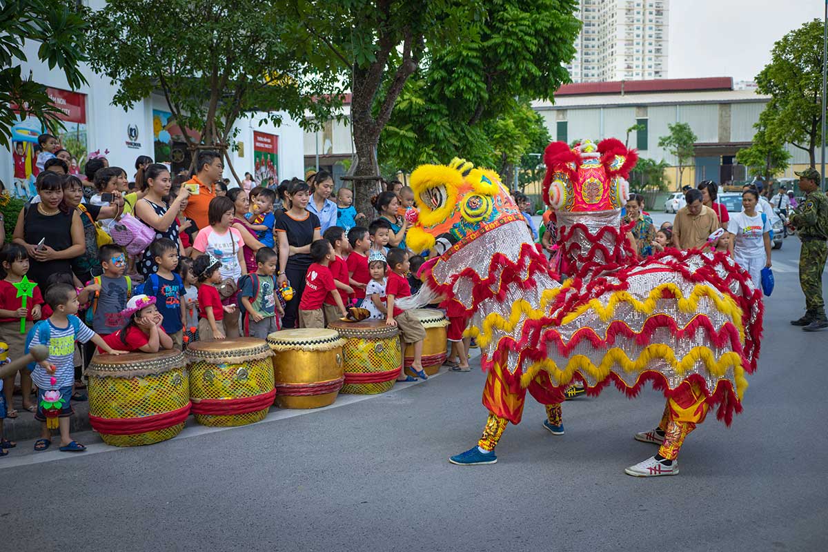 Leeuwendans tijdens het Mid-Autumn Festival in Vietnam, uitgevoerd voor een groep kinderen en families op straat als onderdeel van de Tết Trung Thu-vieringen.