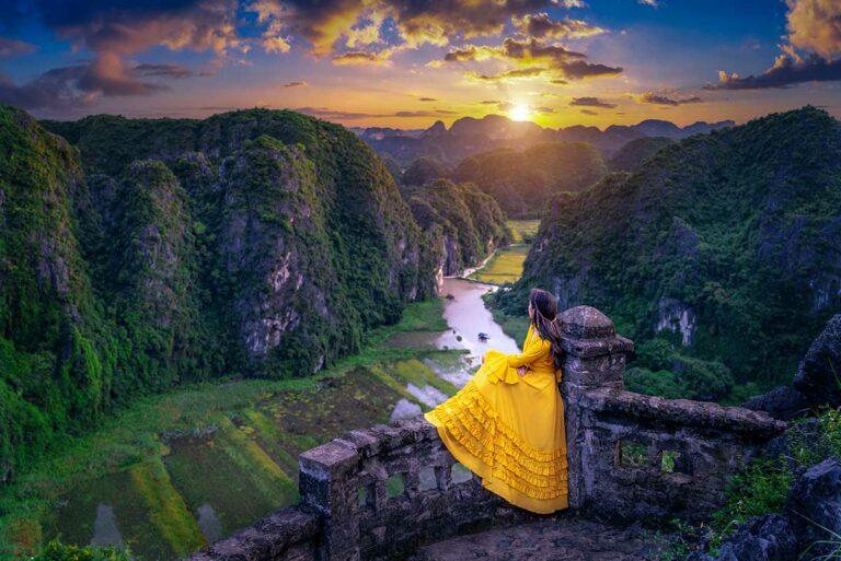 Uitzicht vanaf Mua Cave in Ninh Binh bij zonsondergang, met rivier en rijstvelden tussen kalkstenen heuvels, een van de bekendste fotospots van Noord-Vietnam.