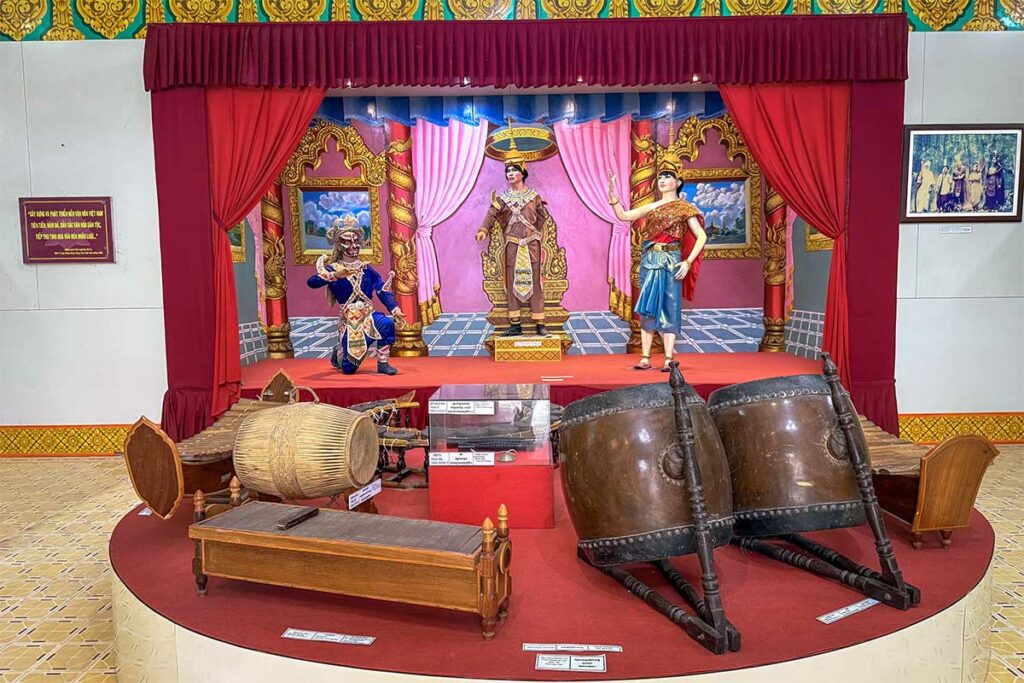 Tentoonstelling in het Museum van de Khmer-cultuur in Tra Vinh met traditionele muziekinstrumenten en beelden in een decor van een klassiek toneel