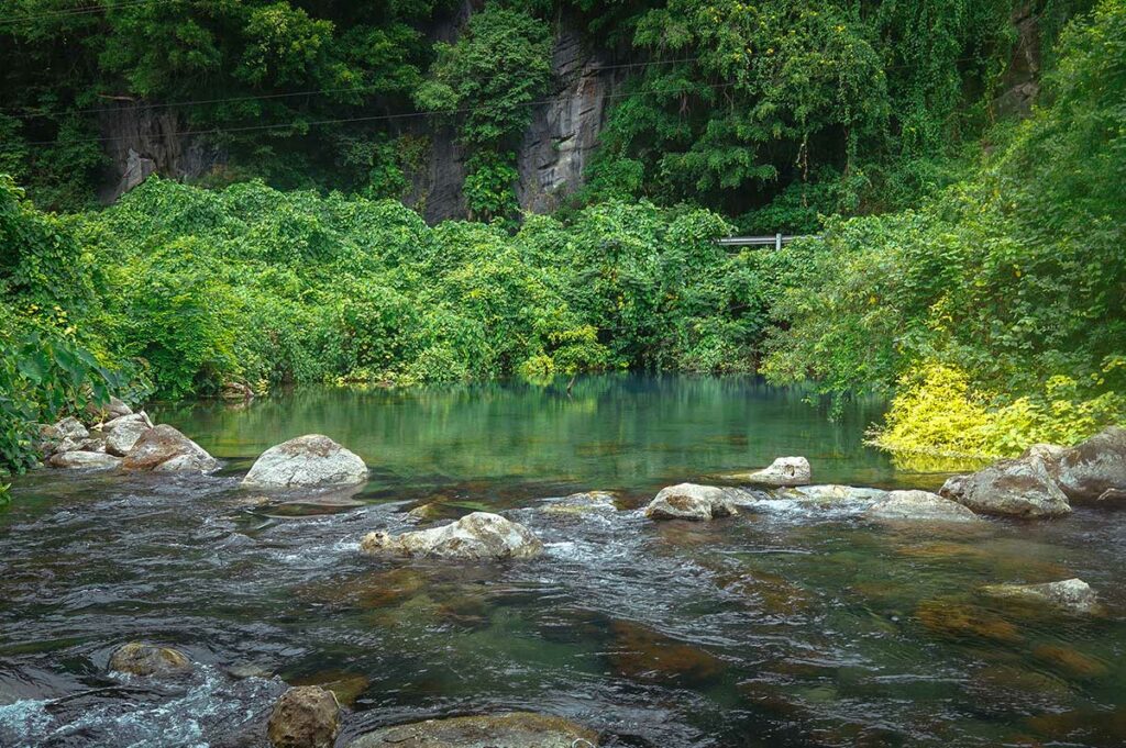 Natuurlijk zwembad met helder water in de Phong Nha Botanic Garden, omgeven door jungle en rotsen