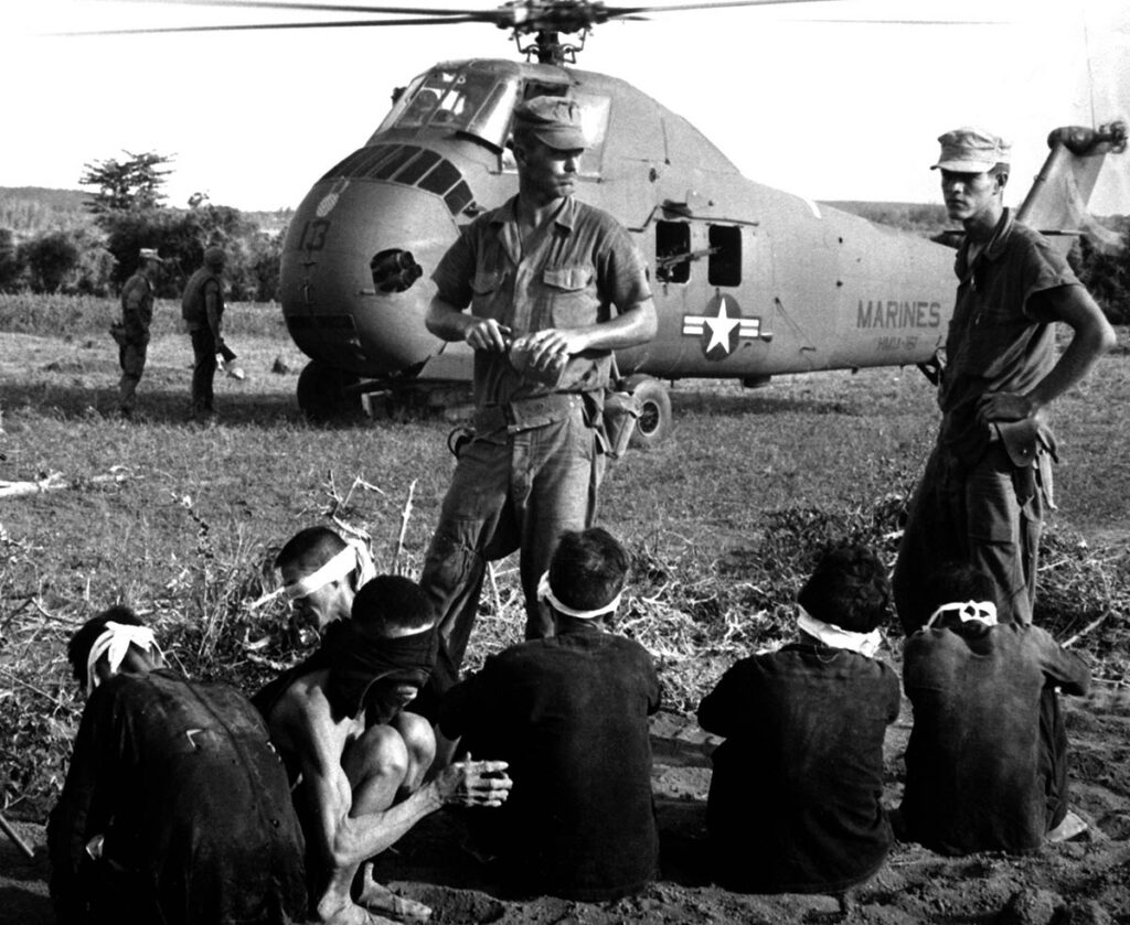 Viet Cong-gevangenen zitten op de grond voor een Amerikaanse UH-34 Seahorse-helikopter tijdens Operation Starlight nabij Chu Lai (1965).