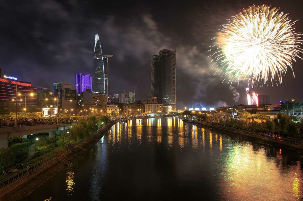Vuurwerk boven de skyline van Ho Chi Minh City tijdens Oud en Nieuw met verlichte wolkenkrabbers langs de rivier